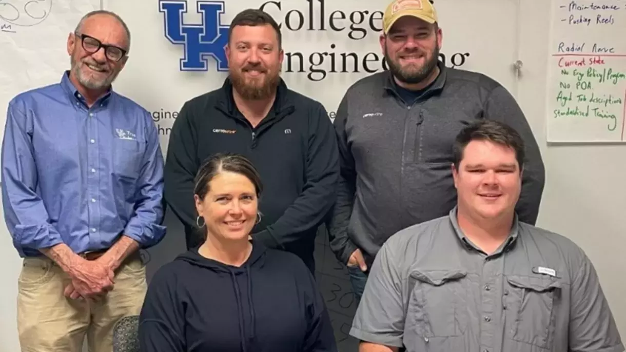 group of people standing in front of a college of engineering sign