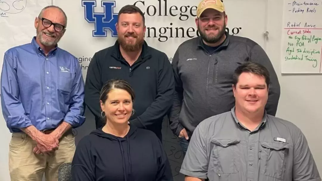 group of people standing in front of a college of engineering sign